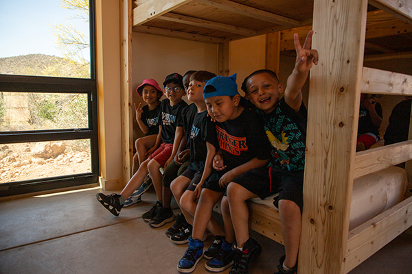 Students smile sitting on the bottom bunk