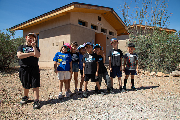 Kinder students pose for a photo outside a cabin