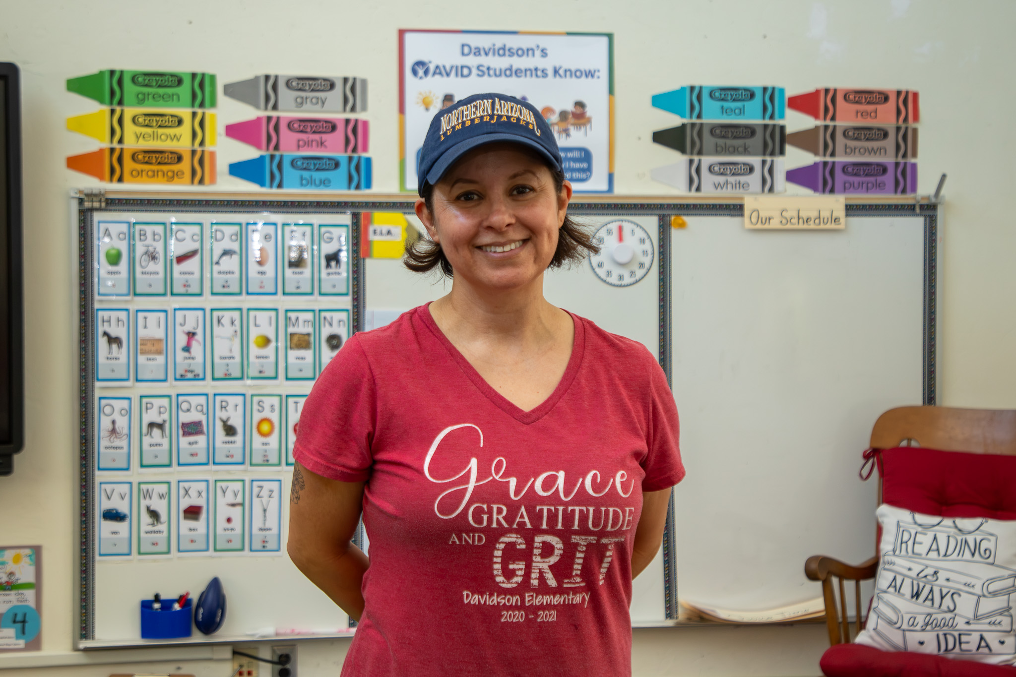 A woman smiles in front of her classroom whiteboards